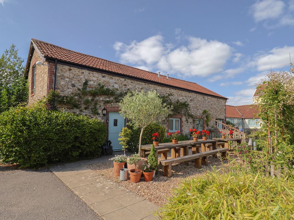 An outdoor seating area with a table and flower pots at The Bull Pen in Colyton