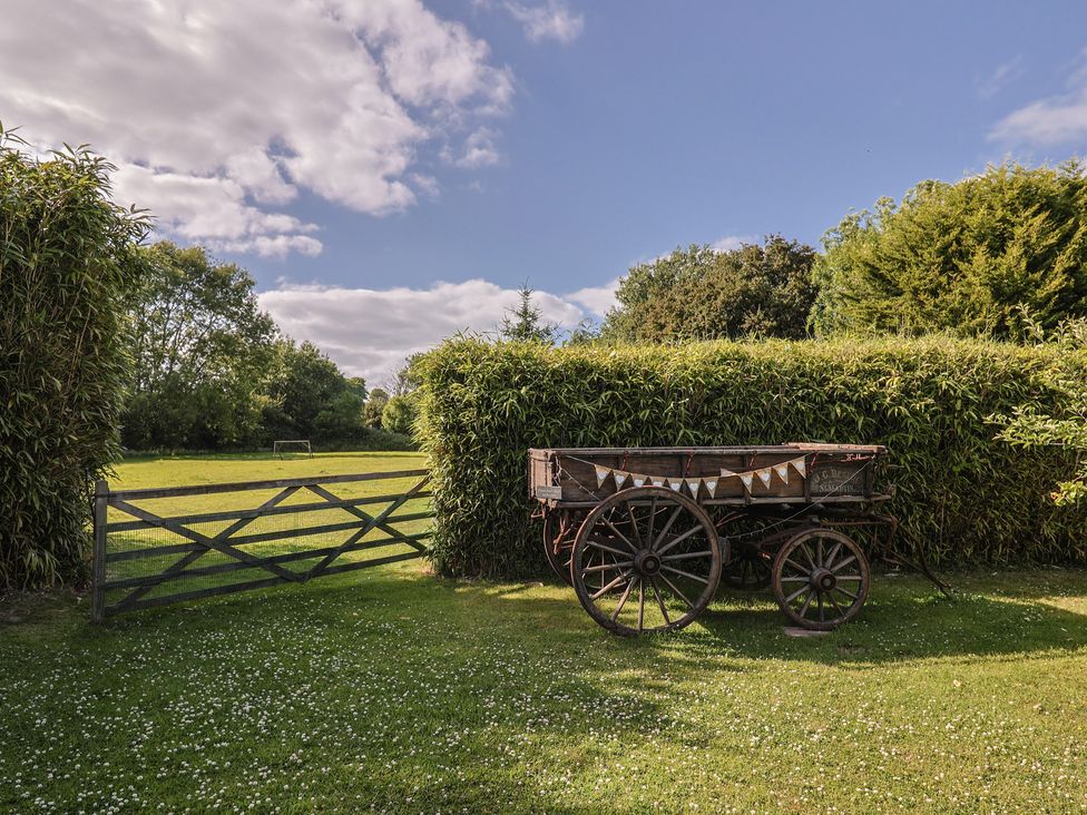 An outdoor area with a wooden cart and a gate at The Bull Pen in Colyton