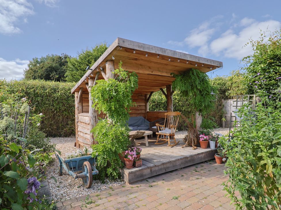 A garden shed with a wooden table and rocking chair at The Bull Pen in Colyton