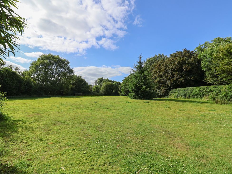 A garden with grass, trees, and a goalpost at The Bull Pen in Colyton