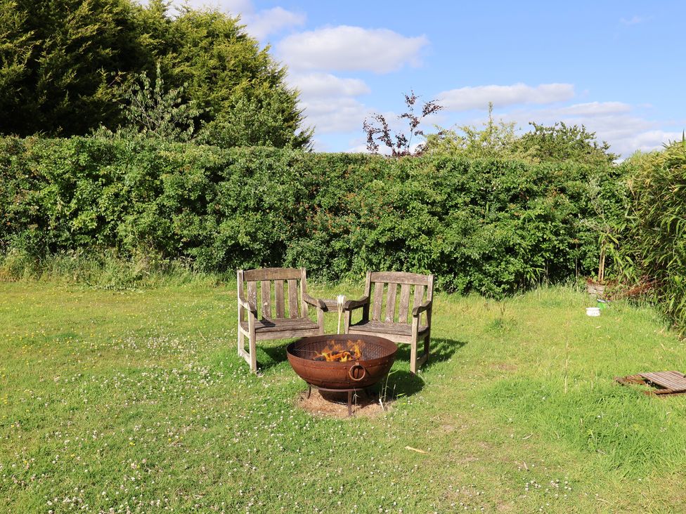 A garden with wooden chairs and a fire pit at The Bull Pen in Colyton