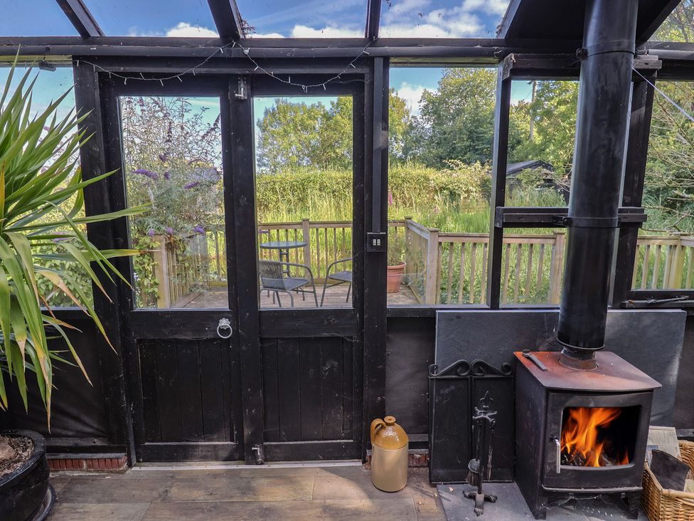 A conservatory with a fireplace and seating overlooking the garden at The Bull Pen in Colyton