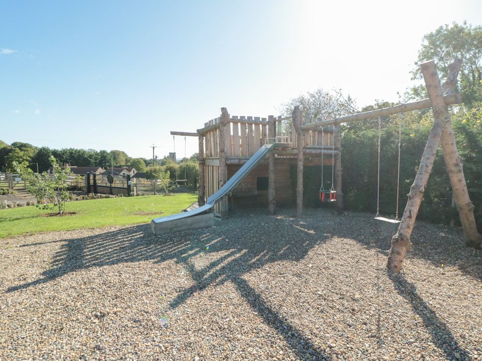 A playhouse with a slide and swings in a garden at Stags Mount in Thornton Dale