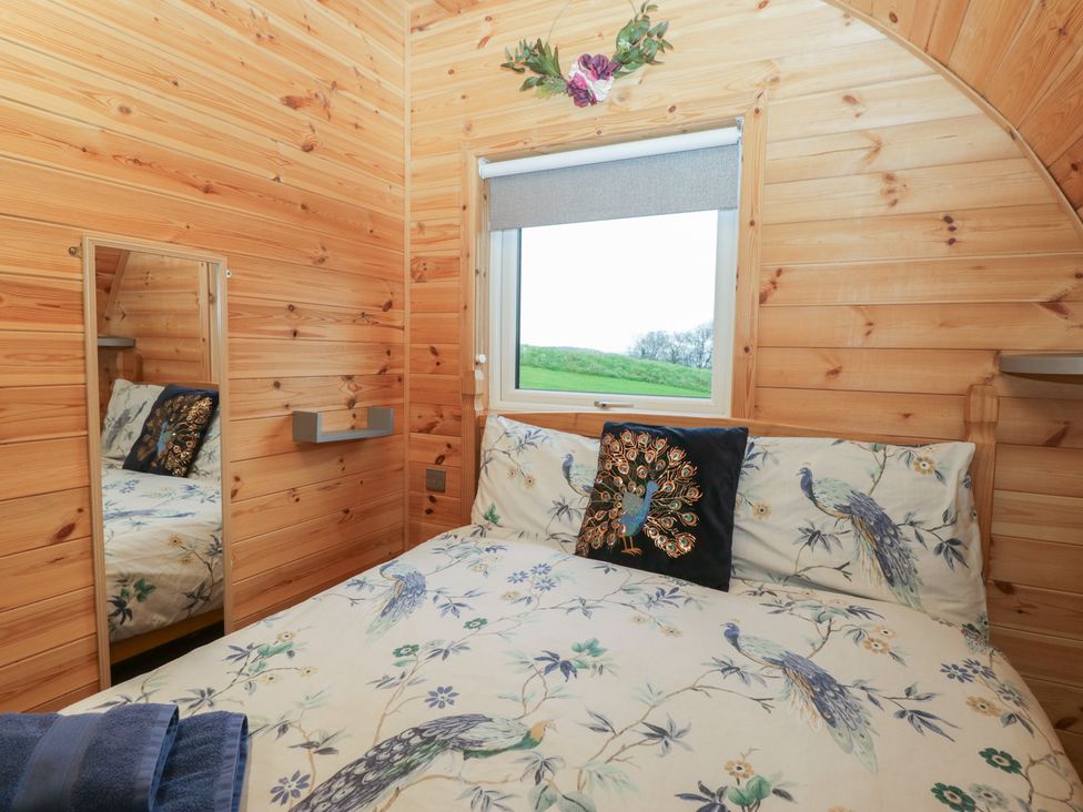 A bedroom with a bed and mirror at Holly in Ulverston