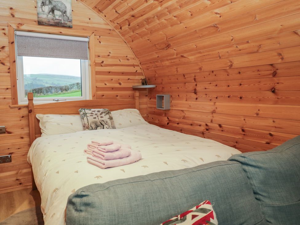 A bedroom with a bed and window in a wooden cabin at Willow in Ulverston