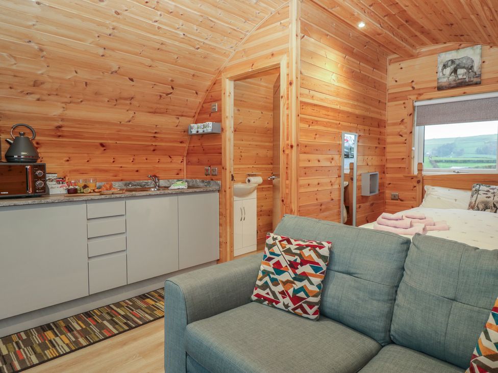 A bedroom with a kitchen area and sofa at Willow in Ulverston