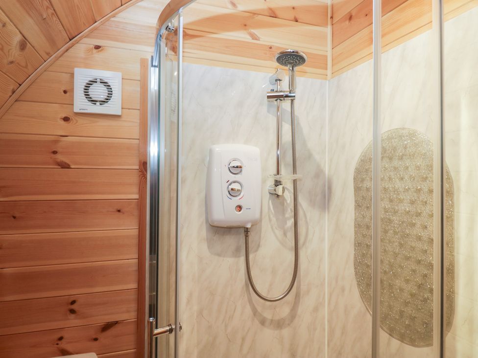 A shower with a glass door and ventilation fan at Willow in Ulverston