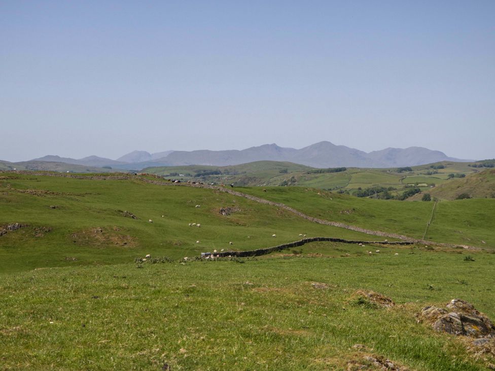 A landscape featuring grass, a stone wall, and mountains at Willow in Ulverston