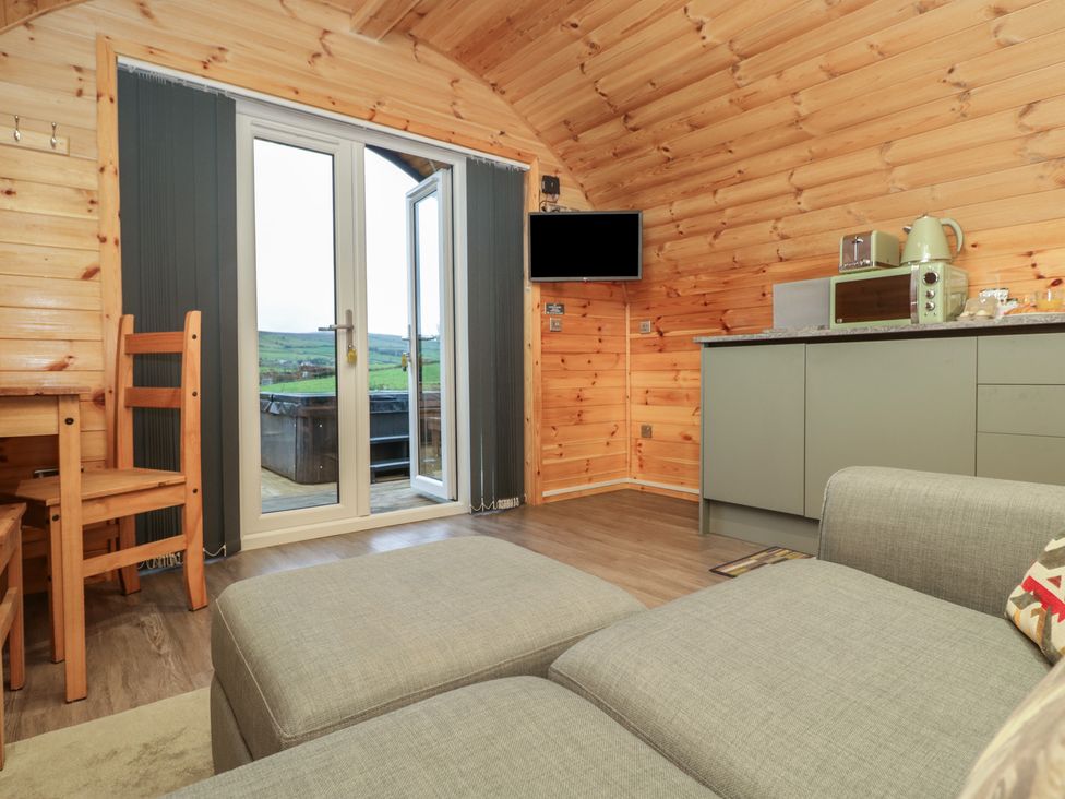 A living room with a sofa and kitchen area at Rowan in Ulverston