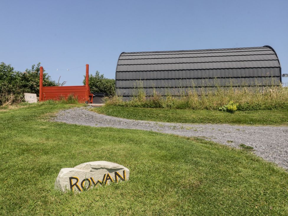 An outdoor area with a sign, shed, and pathway at Rowan in Ulverston