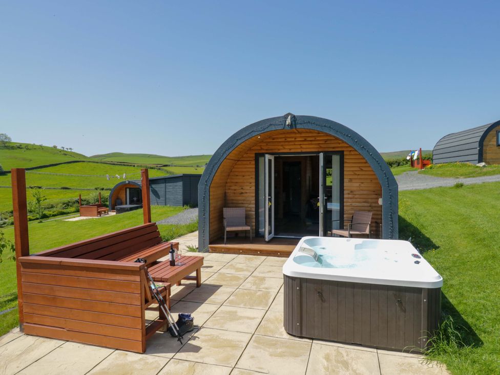 An outdoor area with a hot tub and wooden bench at Cherry in Ulverston