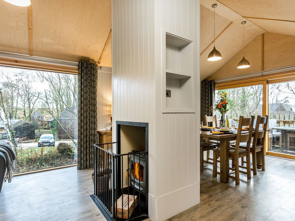 A dining room with a fireplace and a large window at Lodge 16 in Corfe Castle