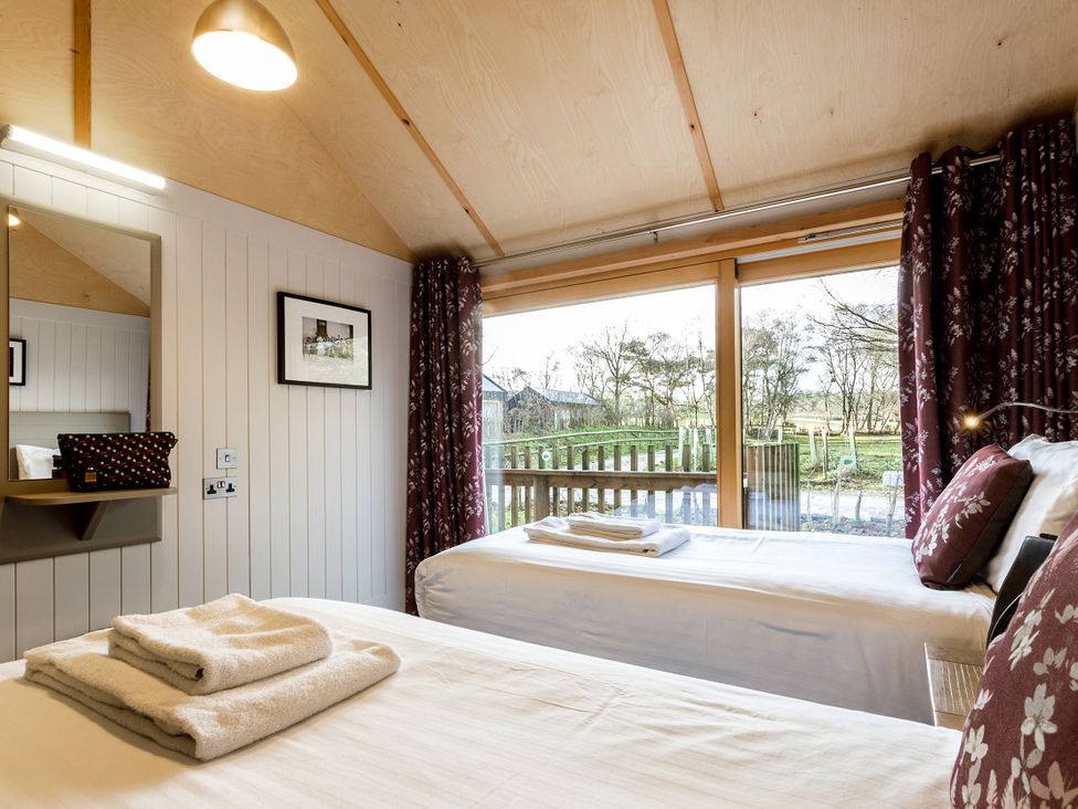 A bedroom with two beds and towels neatly arranged at Lodge 16 in Corfe Castle