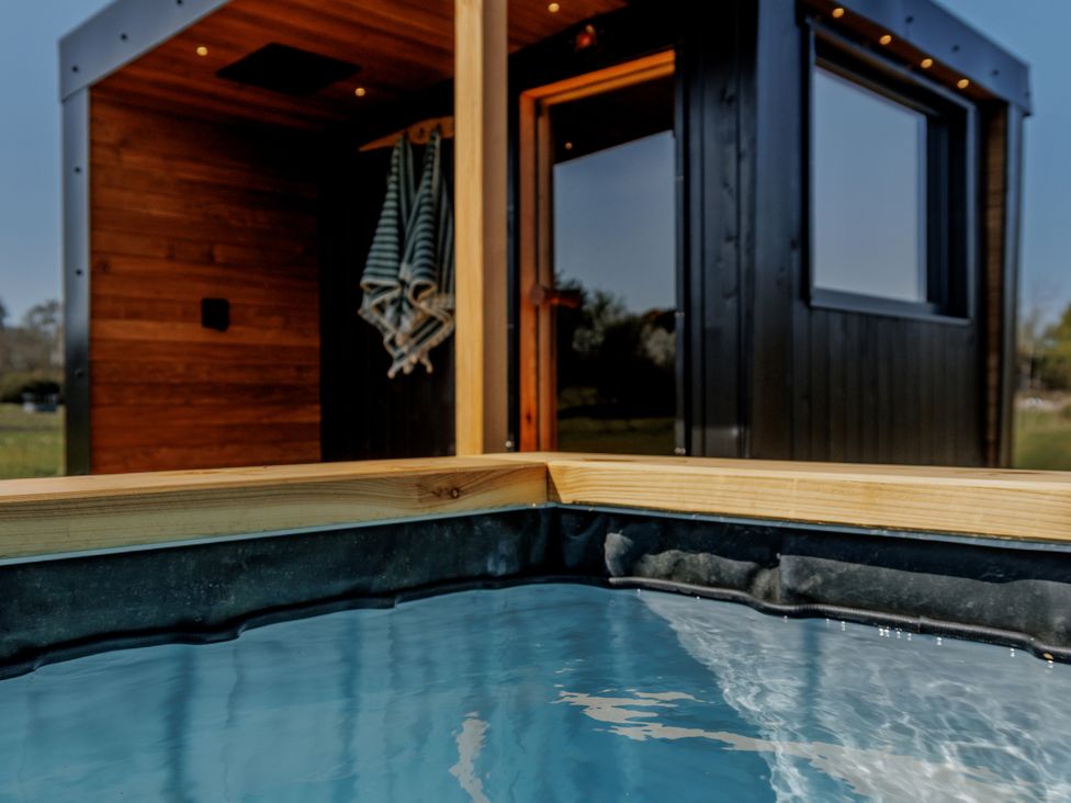 A hot tub with a wooden deck and a building in the background at Lodge 17 Corfe Castle