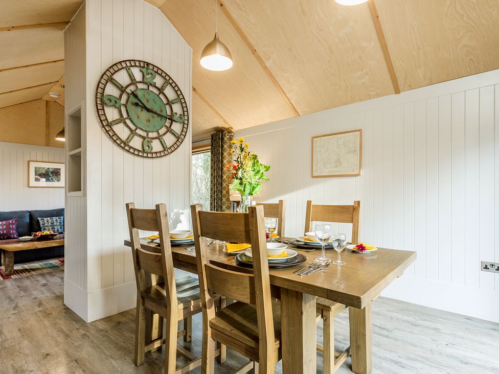 A dining room featuring a wooden table and clock at Lodge 18 in Corfe Castle