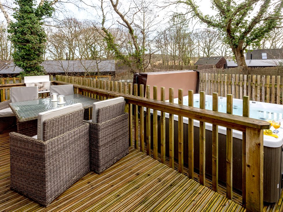 An outdoor patio with a hot tub and seating area at Lodge 18 in Corfe Castle