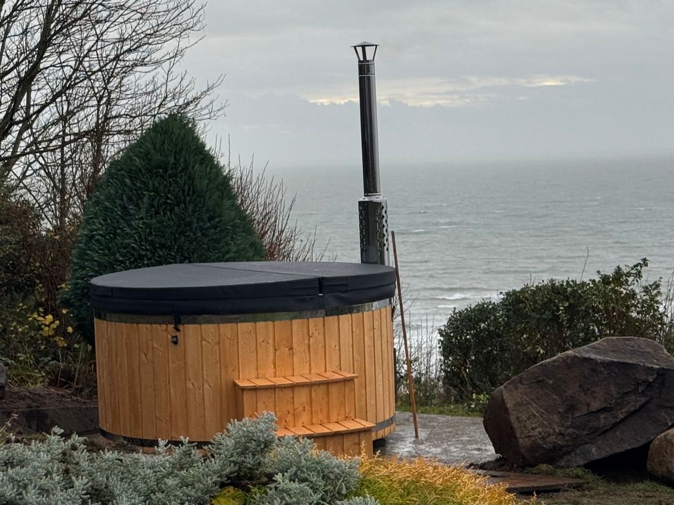 A hot tub with a stove overlooking the sea at Sibrwd Y Mor in Harlech