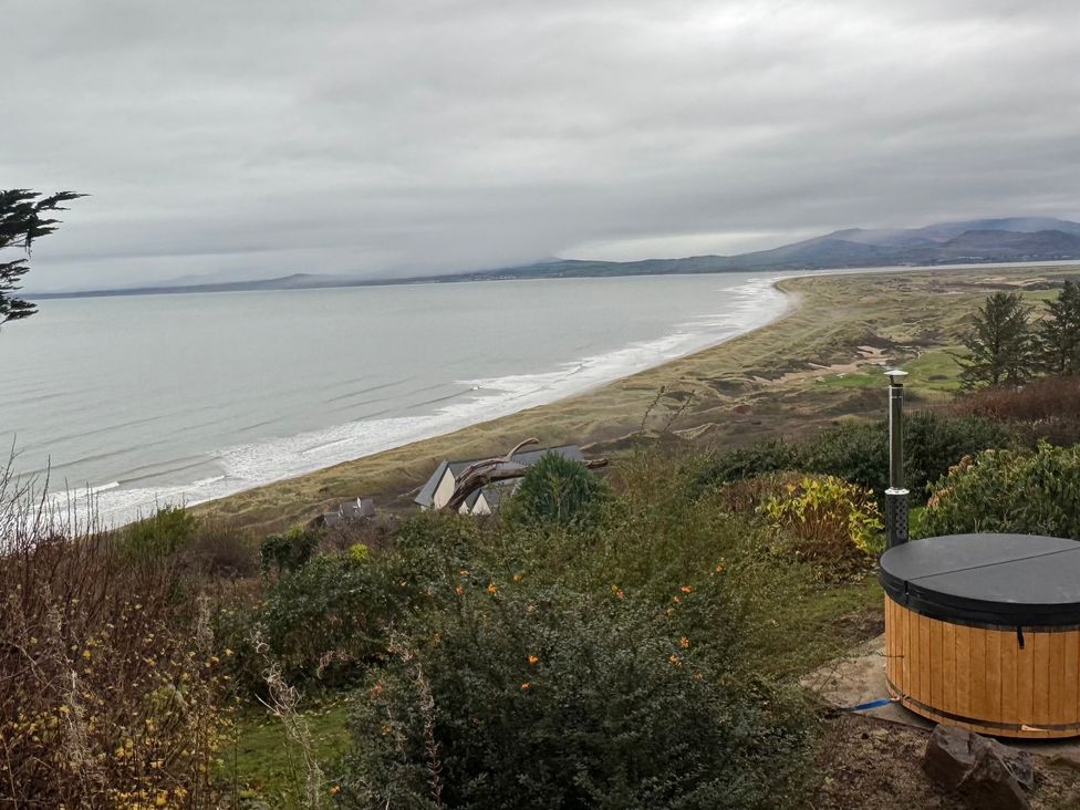 View of the beach and sea with a hot tub in the foreground at Sibrwd Y Mor in Harlech