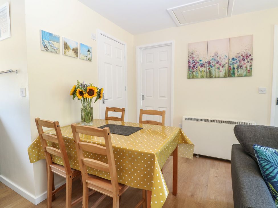 A dining room with a table and flowers at 14 The Dell Mundesley