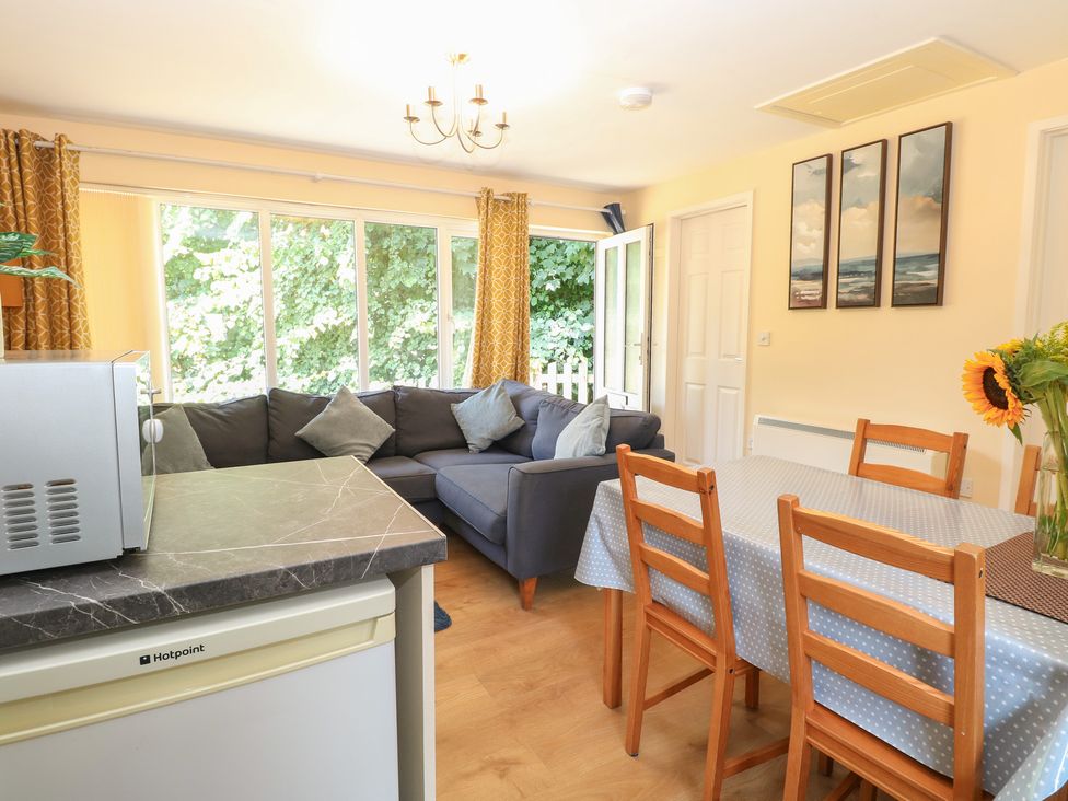 A living room with a sofa and dining area at 15 The Dell Mundesley