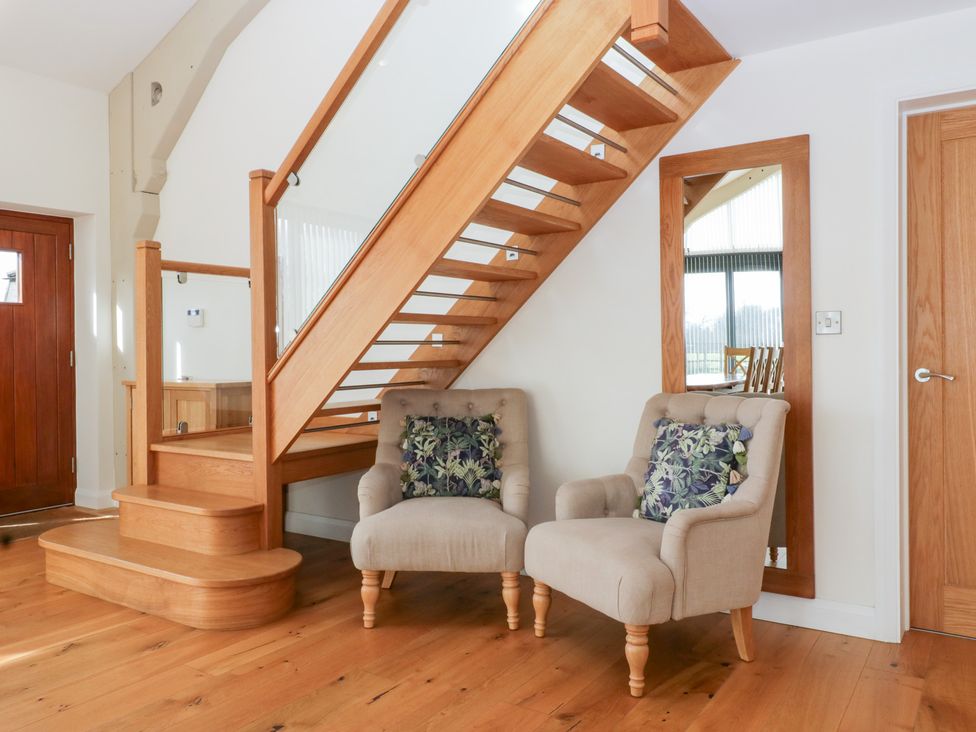 A hallway with a staircase, chairs, and a mirror at Bilsham Meadows in Aust