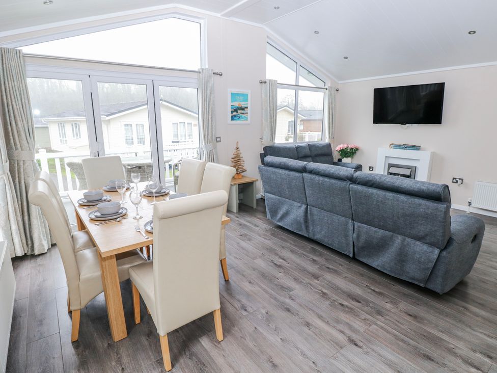 A living room with a dining area and television at Dono's Lodge, Stepaside near Kilgetty, Heritage Park