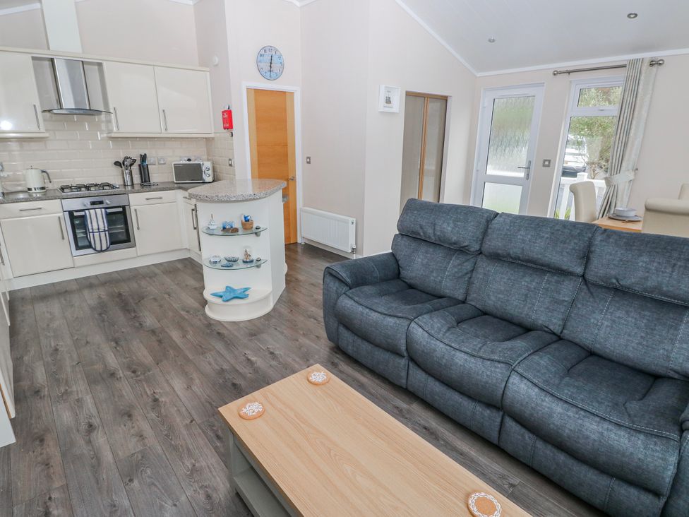 A living room with a kitchen area and a sofa at Dono's Lodge Stepaside near Kilgetty Heritage Park