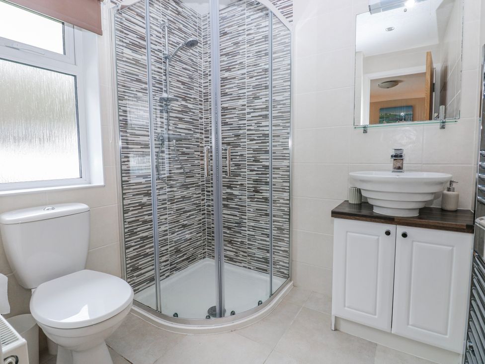 A bathroom with a shower, toilet, and sink at Dono's Lodge Stepaside near Kilgetty, Heritage Park