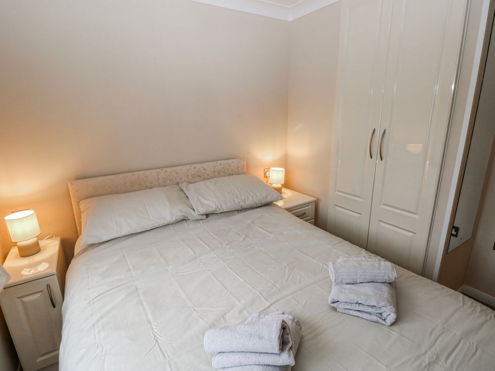 A bedroom with a bed and lamps on either side at Dono's Lodge, Stepaside near Kilgetty, Heritage Park