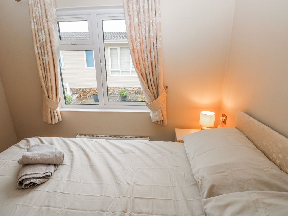 A bedroom with a bed and curtains at Dono's Lodge Stepaside near Kilgetty Heritage Park