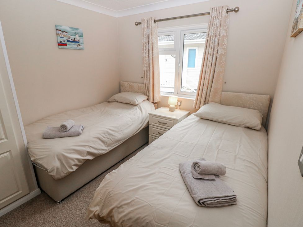 A bedroom with two beds and a bedside table at Dono's Lodge, Stepaside near Kilgetty, Heritage Park