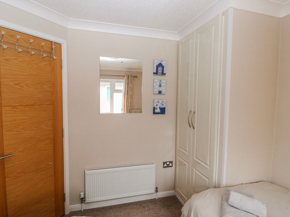 A bedroom with a mirror, wardrobe, and door at Dono's Lodge, Stepaside near Kilgetty, Heritage Park