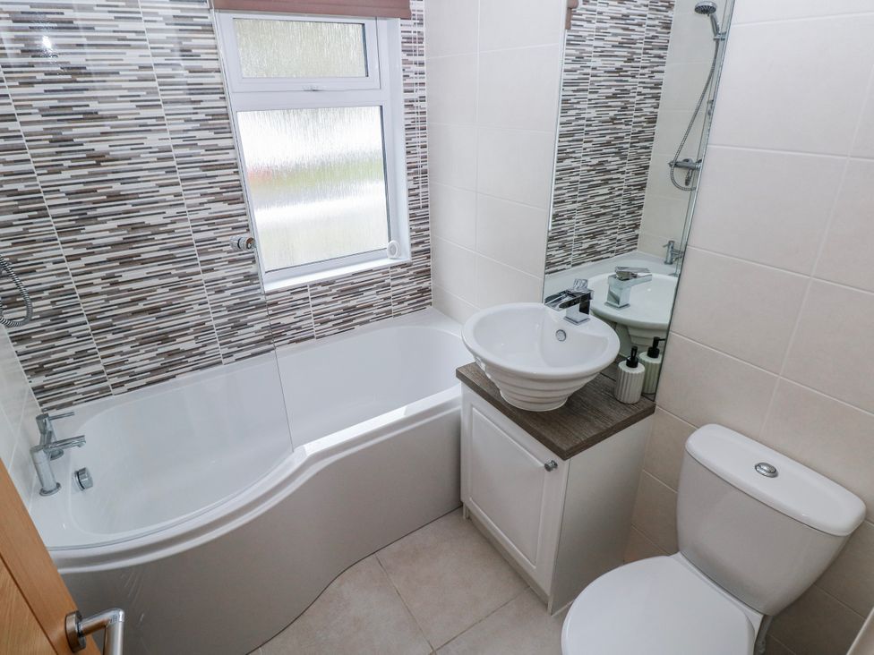 A bathroom with a bathtub, toilet, and sink at Dono's Lodge, Stepaside near Kilgetty, Heritage Park