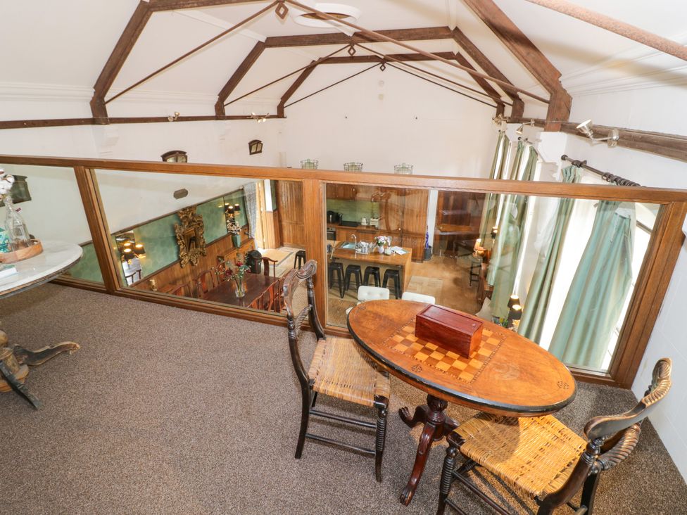 A loft area with a table and chairs overlooking the living space at Chetwynd Lodge Ingestre near Great Haywood