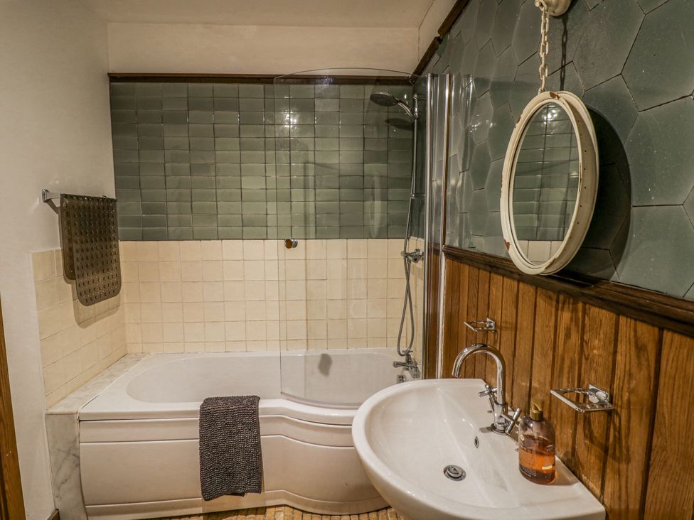 A bathroom with a bathtub, shower, sink, and mirror at Talbot Lodge Ingestre near Great Haywood