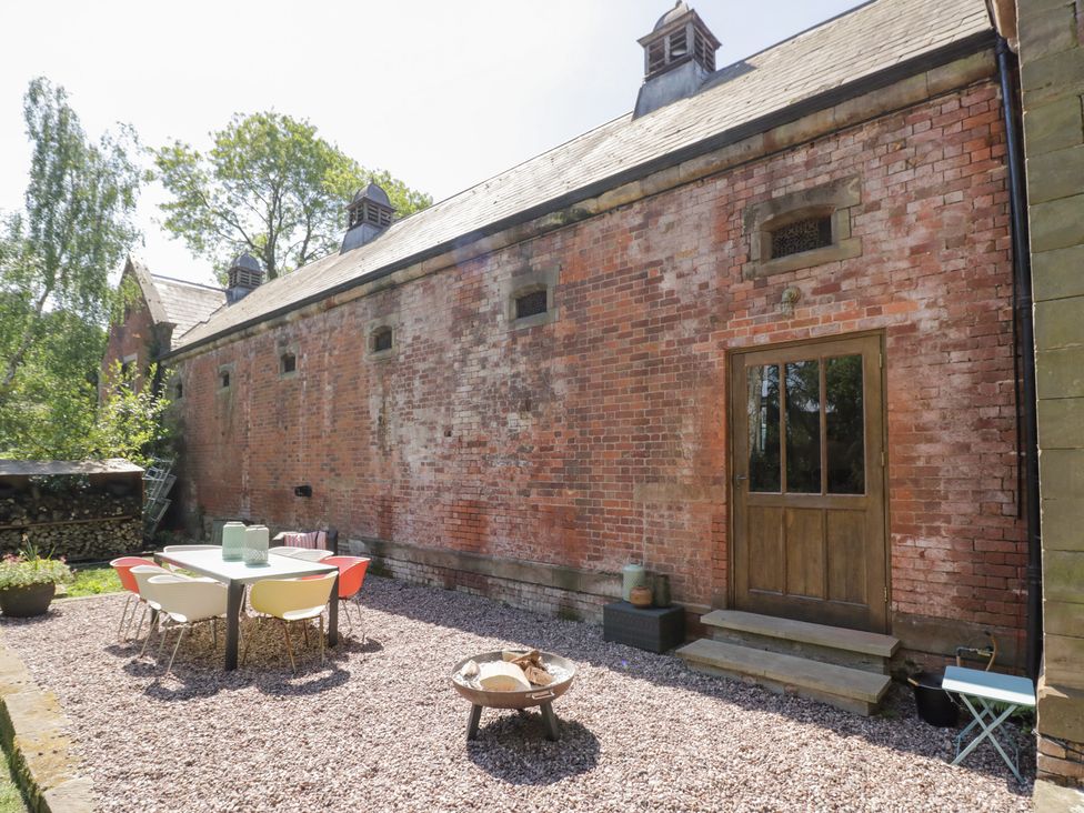 An outdoor area with a table and chairs near a brick wall at Talbot Lodge Ingestre near Great Haywood