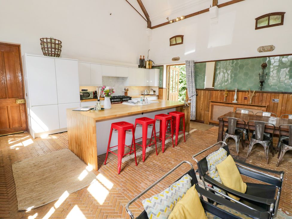 A kitchen with bar stools and a dining table at Talbot Lodge Ingestre near Great Haywood