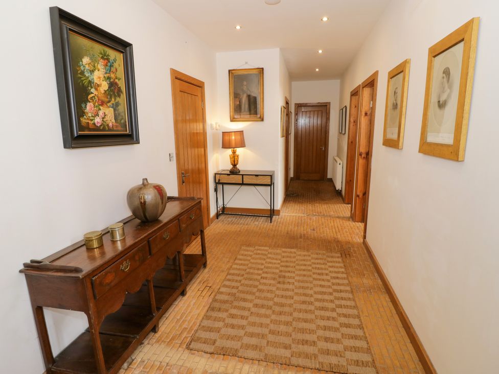 A hallway with a wooden console table and paintings at Talbot Lodge Ingestre near Great Haywood