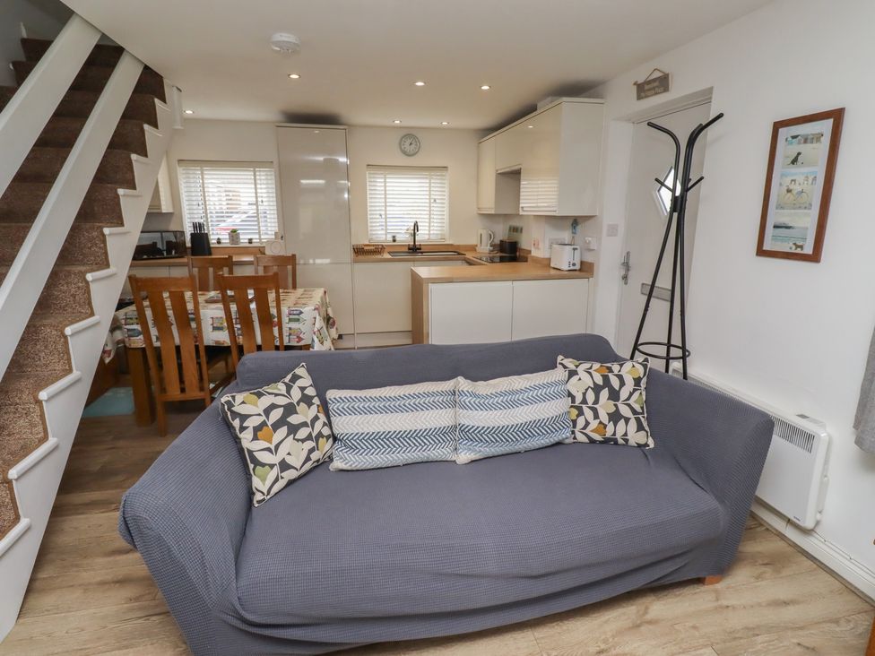 A living room with a sofa and kitchen area at 22 Longstone Park Beadnell