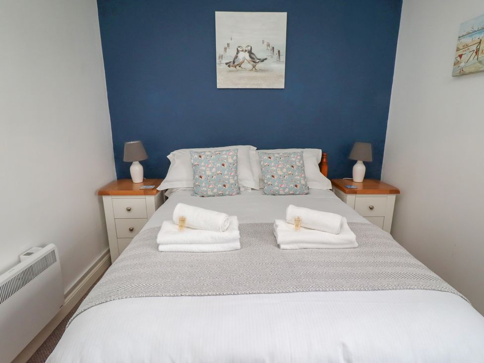 A bedroom with a bed and nightstands at 22 Longstone Park Beadnell
