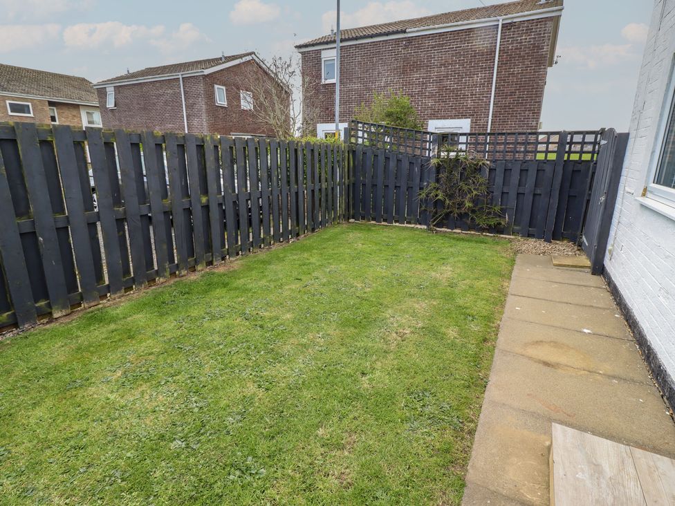 A garden with grass and a fence at 22 Longstone Park Beadnell