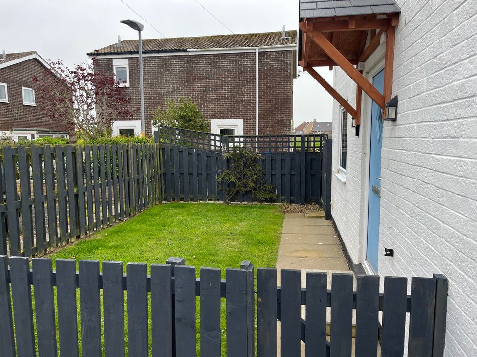 A garden with grass and a wooden fence at 22 Longstone Park Beadnell