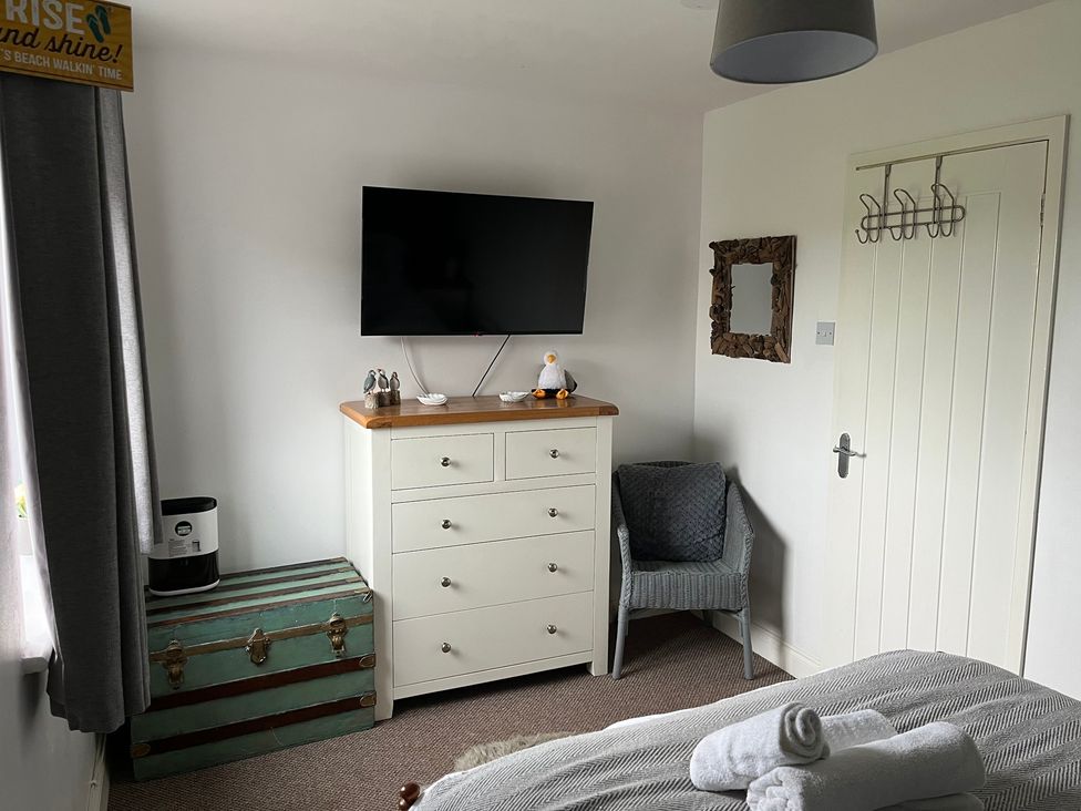 A bedroom with a television, dresser, and armchair at 22 Longstone Park Beadnell