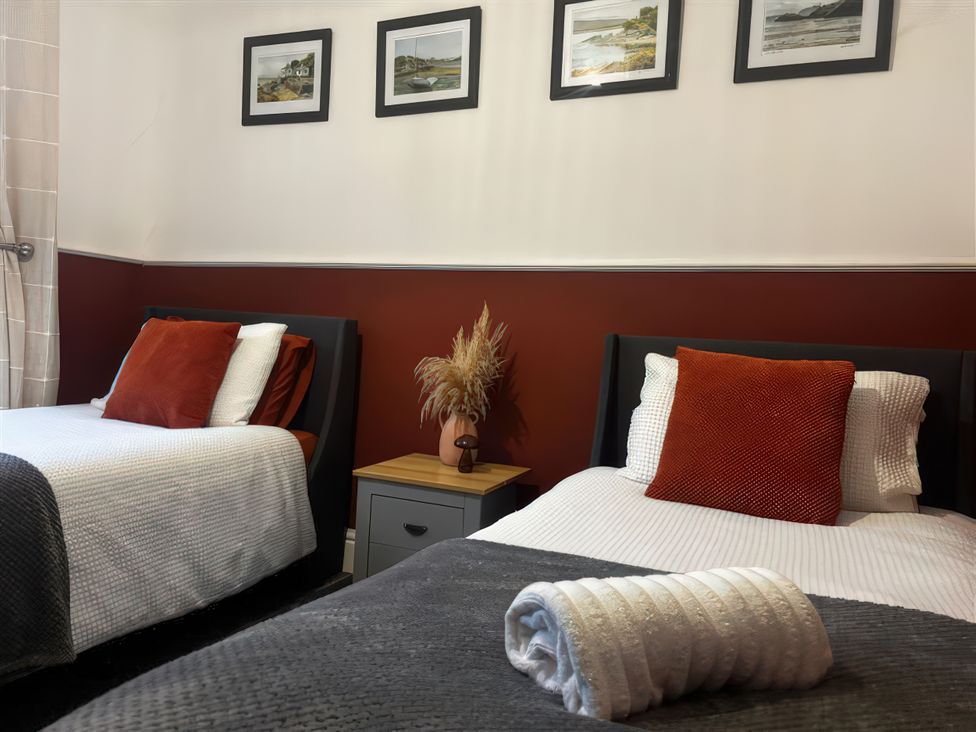 A bedroom with two beds and pictures on the wall at Heol Madog Porthmadog