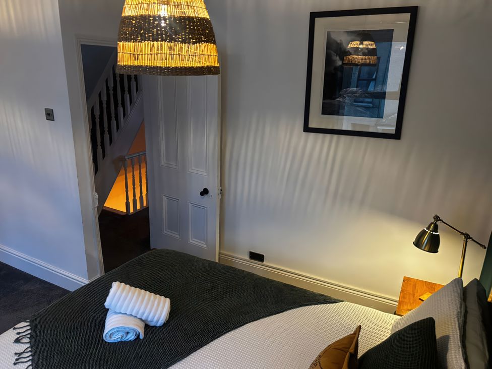A bedroom with a bed, lamp, and door at Heol Madog Porthmadog
