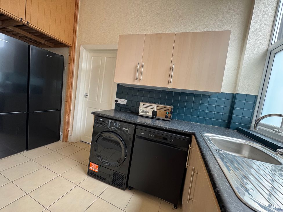 A kitchen with appliances including a washing machine and refrigerator at The Causeway