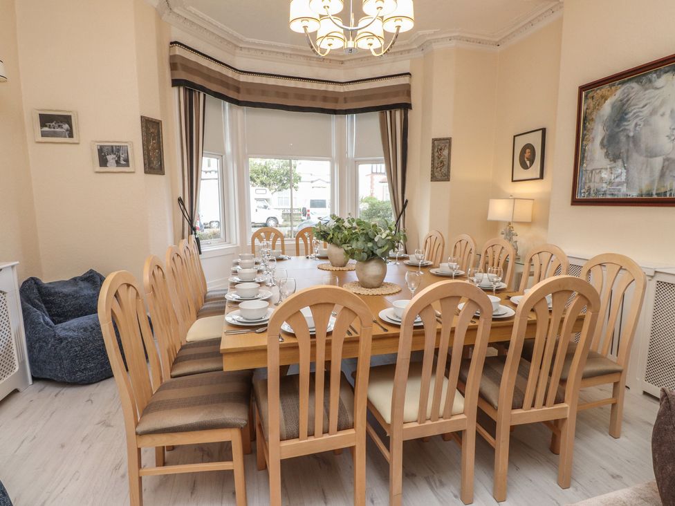 A dining room with a long table set for dinner at The Causeway in Llandudno