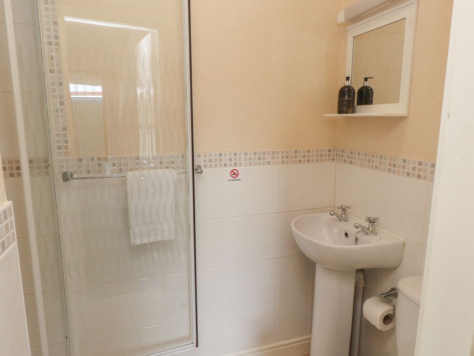 A bathroom with a shower, wash basin, and toilet at The Causeway in Llandudno