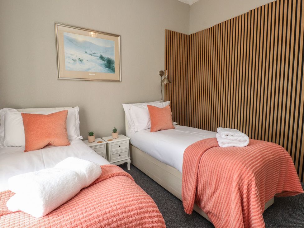 A bedroom with two beds, nightstands, and wall art at The Causeway in Llandudno