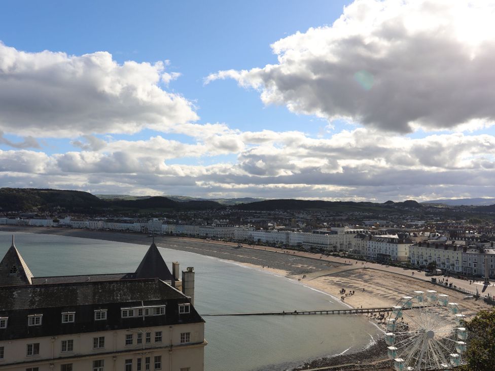 A view of the beach and pier with a ferris wheel at The Causeway in Llandudno